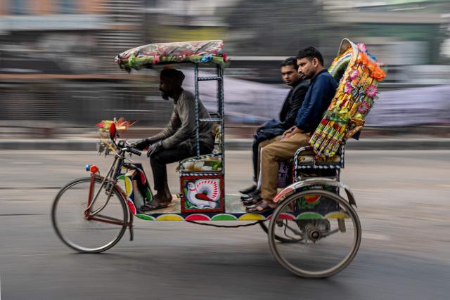 Commuters ride a tricycle rickshaw in Dhaka on February 11, 2026 on the eve of Bangladesh's general elections. (Photo by Mohd RASFAN / AFP)