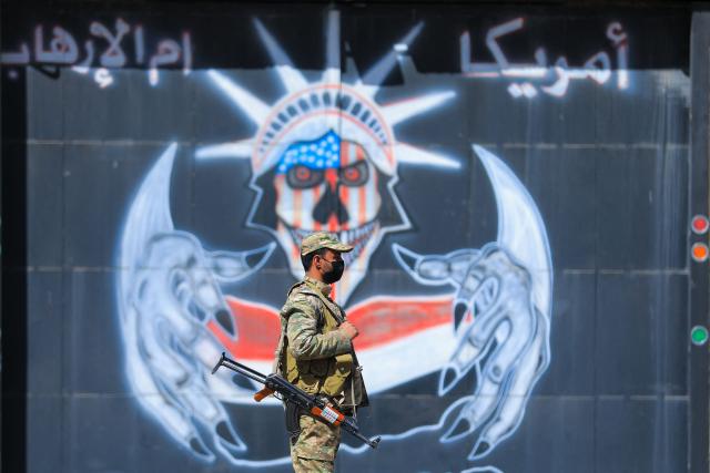 TOPSHOT - A Huthi fighter keeps watch as protesters take part in an anti-US and anti-Israeli demonstration outside the former US embassy building in the Huthi-controlled capital Sanaa on February 11, 2026, marking the anniversary of the US withdrawal from the country in 2015. (Photo by Ahmed Mohammed / AFP)