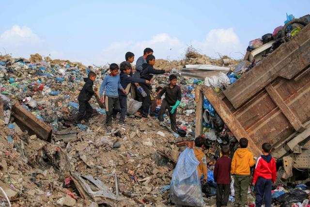 Children sort through waste at a trash mound at the Maghazi camp for Palestinian refugees in the central Gaza Strip on February 11, 2026. Since October 10, a fragile US-sponsored truce in Gaza has largely halted the fighting between Israeli forces and Hamas, but both sides have alleged frequent violations. (Photo by Eyad BABA / AFP)