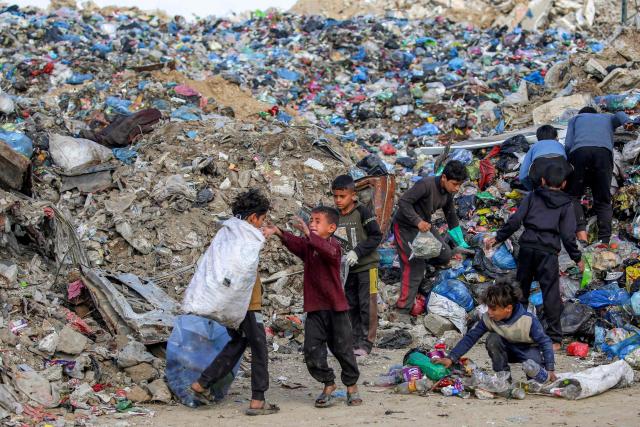Children sort through waste at a trash mound at the Maghazi camp for Palestinian refugees in the central Gaza Strip on February 11, 2026. Since October 10, a fragile US-sponsored truce in Gaza has largely halted the fighting between Israeli forces and Hamas, but both sides have alleged frequent violations. (Photo by Eyad BABA / AFP)