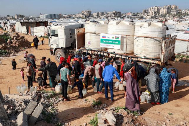 People fill up water containers from a mobile cistern in the Maghazi camp for Palestinian refugees in the central Gaza Strip on February 11, 2026. Since October 10, a fragile US-sponsored truce in Gaza has largely halted the fighting between Israeli forces and Hamas, but both sides have alleged frequent violations. (Photo by Eyad BABA / AFP)