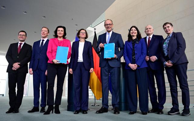 German Minister for Research, Technology and Aerospace Dorothee Baer (3rd L) and German Chancellor Friedrich Merz (4th R) pose with Irene Bertschek (4th L), Chair of Germany's Commission of Experts on Research and Innovation (EFI), and commission members Guido Buenstorf (L), Joachim Henkel (2nd L), Friederike Welter (R), Christoph M Schmidt (2nd R) and Carolin Haeussler after they handed over their annual report to the German government on February 11, 2026 at the Chancellery in Berlin. (Photo by John MACDOUGALL / AFP)