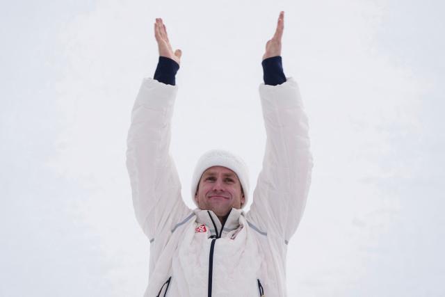 USA's silver medalist Ryan Cochran-Siegleon raises his arms on the podium of the men's super-G alpine skiing event during the Milano Cortina 2026 Winter Olympic Games at the Stelvio Ski Centre in Bormio (Valtellina) on February 11, 2026. (Photo by Dimitar DILKOFF / AFP)