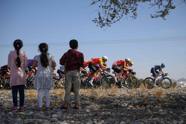 Children look at the pack riding during the 5th and last stage of the Tour of Oman cycling race from Nizwa to Green Mountain, on February 11, 2026. (Photo by Loic VENANCE / AFP)