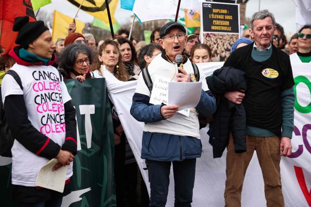 Members of "Collectif de soutien aux victimes des pesticides de l'Ouest" (CSVPO) Bernard Morel (C) speaks during a demonstration for agriculture, the environment and health, against the Duplomb law, at the initiative of dozens of NGOs and farmers' organizations, in front of the National Assembly in Paris on February 11, 2026. Senator Laurent Duplomb's law, adopted by Parliament in early July, facilitates water storage and the expansion of livestock buildings. But another measure concentrated indignation: the conditional reintroduction of acetamiprid, a pesticide from the neonicotinoid family banned in France but authorized elsewhere in Europe and accused of being a "bee killer" by its critics. (Photo by Guillaume BAPTISTE / AFP)