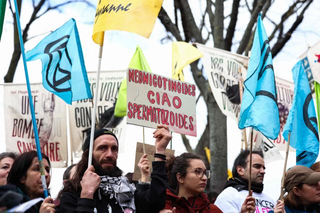 Protestors hold signs during a demonstration for agriculture, the environment and health, against the Duplomb law, at the initiative of dozens of NGOs and farmers' organizations, in front of the National Assembly in Paris on February 11, 2026. Senator Laurent Duplomb's law, adopted by Parliament in early July, facilitates water storage and the expansion of livestock buildings. But another measure concentrated indignation: the conditional reintroduction of acetamiprid, a pesticide from the neonicotinoid family banned in France but authorized elsewhere in Europe and accused of being a "bee killer" by its critics. (Photo by Guillaume BAPTISTE / AFP)