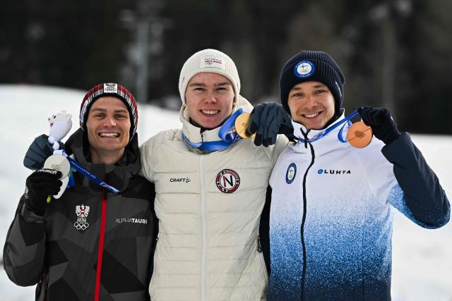 (From L) Silver medalist Austria's Johannes Lamparter, gold medallist Norway's Jens Luraas Oftebro and bronze medallist Finland's Eero Hirvonen celebrate on the podium following the nordic combined individual Gundersen normal hill/10km event at Tesero Cross Country Stadium at Lago di Tesero (Val di Fiemme) during the Milano Cortina 2026 Winter Olympic Games on February 11, 2026. (Photo by Javier SORIANO / AFP)