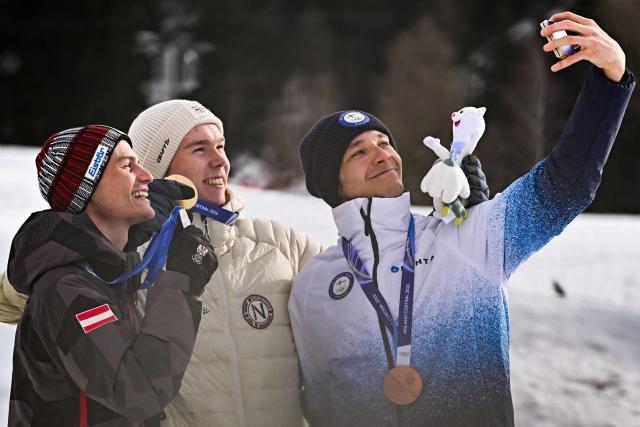 (From L) Silver medalist Austria's Johannes Lamparter, gold medallist Norway's Jens Luraas Oftebro and bronze medallist Finland's Eero Hirvonen celebrate on the podium following the nordic combined individual Gundersen normal hill/10km event at Tesero Cross Country Stadium at Lago di Tesero (Val di Fiemme) during the Milano Cortina 2026 Winter Olympic Games on February 11, 2026. (Photo by Javier SORIANO / AFP)