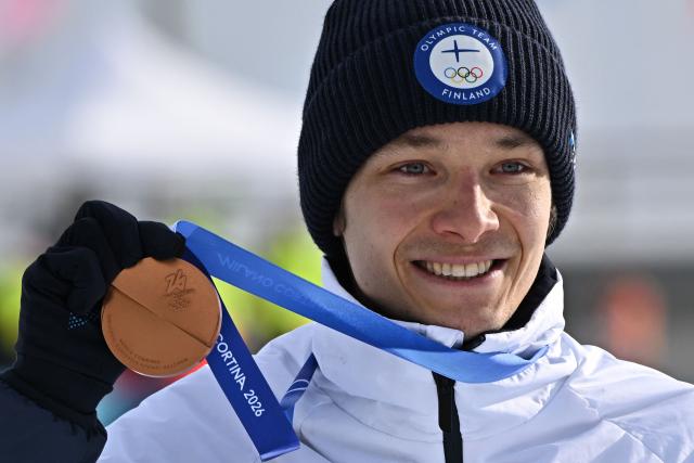 Bronze medallist Finland's Eero Hirvonen celebrates on the podium following the nordic combined individual Gundersen normal hill/10km event at Tesero Cross Country Stadium at Lago di Tesero (Val di Fiemme) during the Milano Cortina 2026 Winter Olympic Games on February 11, 2026. (Photo by Javier SORIANO / AFP)