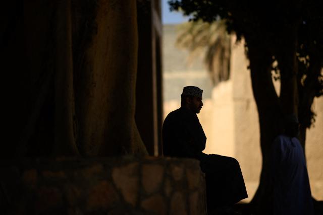 A man sits in front of the entrance of the souk of Nizwa, prior to the presentation of the 5th and last stage of the Tour of Oman cycling race from Nizwa to Green Mountain, on February 11, 2026. (Photo by Loic VENANCE / AFP)