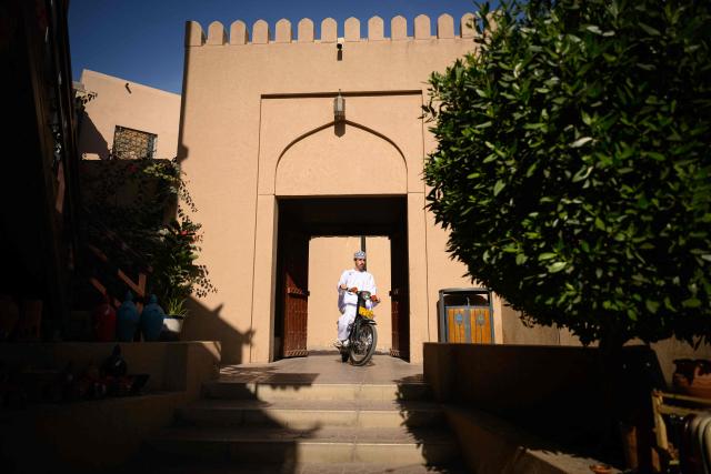 A local resident rides his sccoter in the souk of Nizwa, prior to the presentation of the 5th and last stage of the Tour of Oman cycling race from Nizwa to Green Mountain, on February 11, 2026. (Photo by Loic VENANCE / AFP)