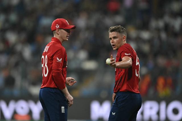England's Sam Curran (R) and captain Harry Brook interact during the 2026 ICC Men's T20 Cricket World Cup group stage match between England and West Indies at the Wankhede Stadium in Mumbai on February 11, 2026. (Photo by Indranil MUKHERJEE / AFP)