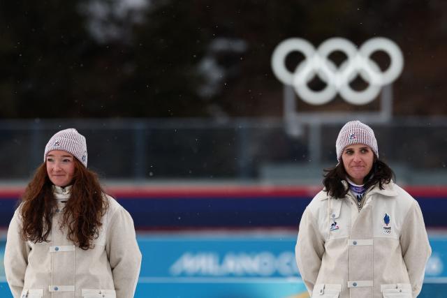 (L-R) Silver medallist France's Lou Jeanmonnot and gold medallist France's Julia Simon attend the victory ceremony on the podium of the women's biathlon 15km individual event during the Milano Cortina 2026 Winter Olympic Games at the Anterselva Biathlon Arena (Sudtirol Arena) in Anterselva (Val Pusteria) on February 11, 2026. (Photo by FRANCK FIFE / AFP)