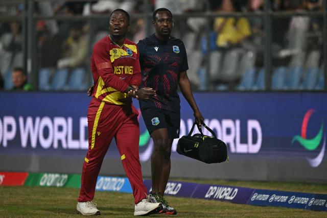 West Indies' Sherfane Rutherford (L) walks back to the pavilion after his injury during the 2026 ICC Men's T20 Cricket World Cup group stage match between England and West Indies at the Wankhede Stadium in Mumbai on February 11, 2026. (Photo by Indranil MUKHERJEE / AFP)