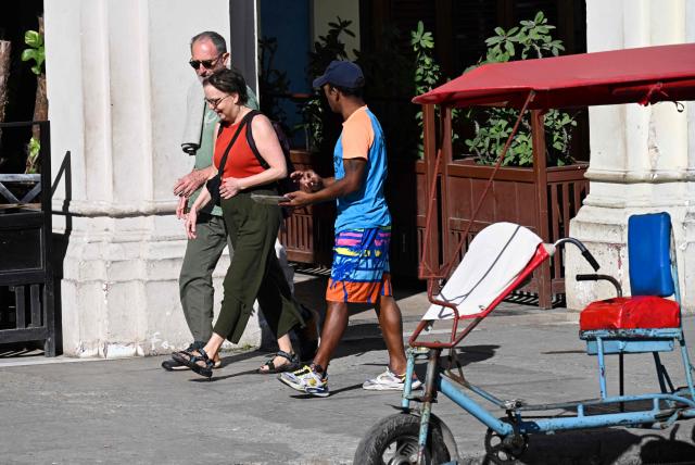 Tourists walk along a street in Havana on February 11, 2026. (Photo by YAMIL LAGE / AFP)