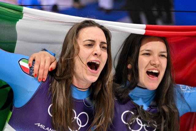 Italy's Andrea Voetter (L) and Italy's Marion Oberhofer (R) celebrate after crossing the finish line to win the luge women's doubles run 2 at Cortina Sliding Centre during the Milano Cortina 2026 Winter Olympic Games in Cortina d'Ampezzo on February 11, 2026. (Photo by Tiziana FABI / AFP)