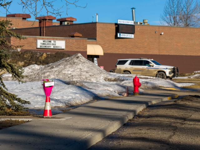 Flowers are left outside of Tumbler Ridge secondary school building where a shooting took place, leaving at least nine people dead in the small town of Tumbler Ridge, British Columbia, on February 11, 2026. Canada was in mourning Wednesday, Prime Minister Mark Carney said, after a lone shooter killed at least nine people, including seven at a school, and injured dozens more in a remote western town. (Photo by Eagle Vision Agency / AFP)