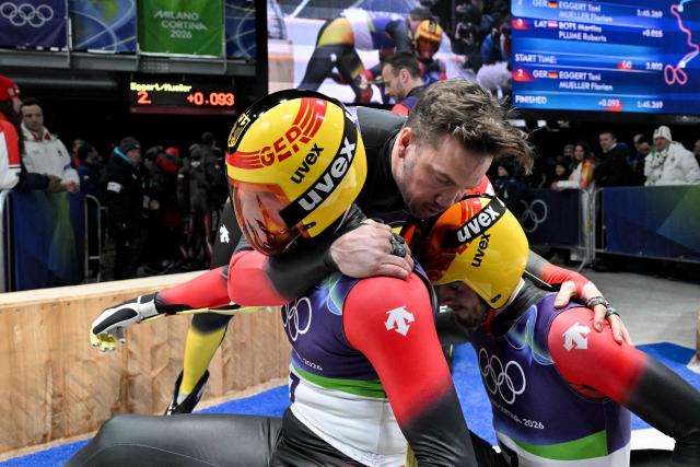Germany's Tobia Wendl and Tobias Arlt celebrate winning the bronze medal in the finish area of the luge men's doubles run 2 at Cortina Sliding Centre during the Milano Cortina 2026 Winter Olympic Games in Cortina d'Ampezzo on February 11, 2026. (Photo by Tiziana FABI / AFP)