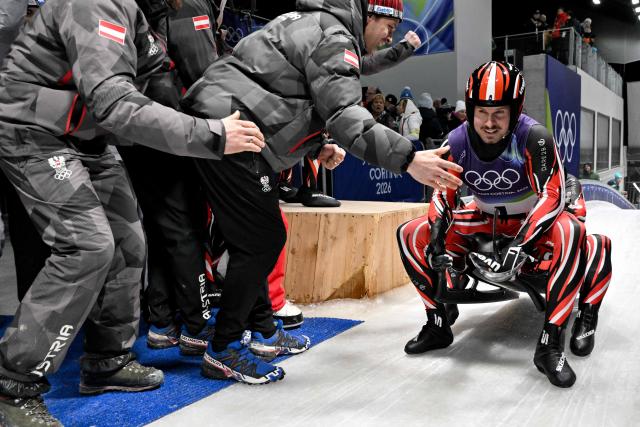 Austria's Thomas Steu with Wolfgang Kindl celebrate winning the silver medal in the finish area of the luge men's doubles run 2 at Cortina Sliding Centre during the Milano Cortina 2026 Winter Olympic Games in Cortina d'Ampezzo on February 11, 2026. (Photo by Tiziana FABI / AFP)