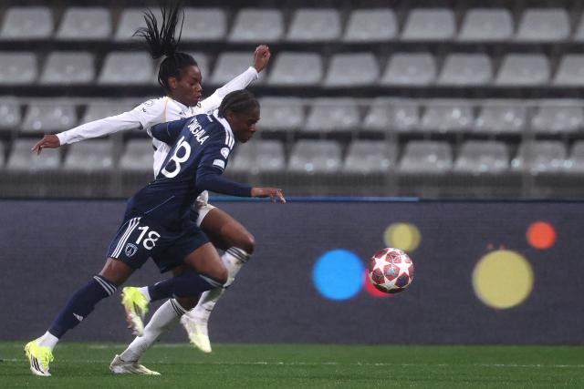 Real Madrid's French forward #20 Naomie Feller (L) and Paris FC's French defender #18 Melween Ndongala (R) fight for the ball during the UEFA Women's Champions League knockout round first leg play-off football match between Paris FC and Real Madrid at the Stade Charlety, in Paris, on February 11, 2026. (Photo by Guillaume BAPTISTE / AFP)