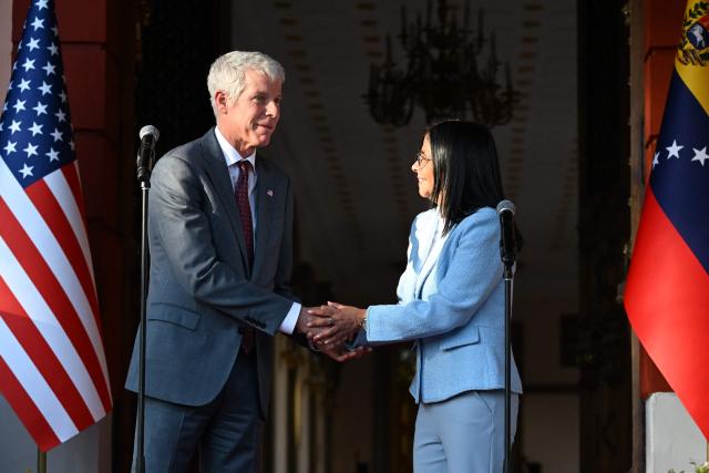 US Secretary of Energy Chris Wright (L) sheakes hands with Venezuela's acting president Delcy Rodriguez during a press conference after a meeting at the Miraflores Presidential Palace in Caracas on February 11, 2026. US Energy Secretary Chris Wright arrived in Venezuela on February 11 for talks with acting president Delcy Rodriguez and oil industry executives on harnessing the country's vast crude reserves. (Photo by Juan BARRETO / AFP)