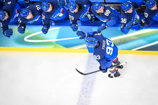 Italy's #93 Luca Frigo celebrates with teammates after scoring his team first goal during the men's preliminary round Group B Ice Hockey match between Sweden and Italy at the Milano Santagiulia Ice Hockey Arena during the Milano Cortina 2026 Winter Olympic Games in Milan, on February 11, 2026. (Photo by Alexander NEMENOV / AFP)