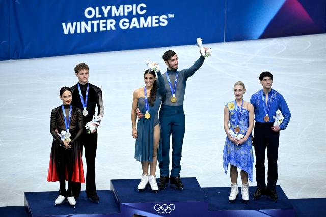 (L-R) Silver medallists USA's Madison Chock and Evan Bates, gold medallists France's Laurence Fournier Beaudry and Guillaume Cizeron and bronze medallists Canada's Piper Gilles and Paul Poirier pose on the podium of the figure skating ice dance-free dance final during the Milano Cortina 2026 Winter Olympic Games at Milano Ice Skating Arena in Milan on February 11, 2026. (Photo by WANG Zhao / AFP)