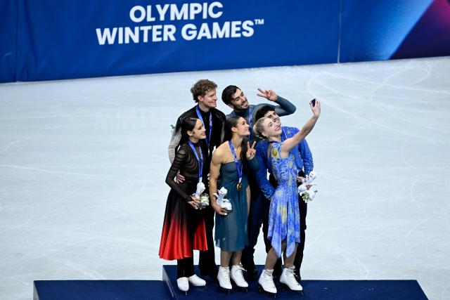 (L-R) Silver medallists USA's Madison Chock and Evan Bates, gold medallists France's Laurence Fournier Beaudry and Guillaume Cizeron and bronze medallists Canada's Piper Gilles and Paul Poirier take their selfie on the podium of the figure skating ice dance-free dance final during the Milano Cortina 2026 Winter Olympic Games at Milano Ice Skating Arena in Milan on February 11, 2026. (Photo by WANG Zhao / AFP)