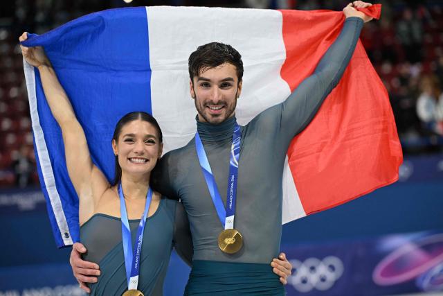 Gold medallists France's Laurence Fournier Beaudry and Guillaume Cizeron pose with the French flag on the podium of the figure skating ice dance-free dance final during the Milano Cortina 2026 Winter Olympic Games at Milano Ice Skating Arena in Milan on February 11, 2026. (Photo by Gabriel BOUYS / AFP)