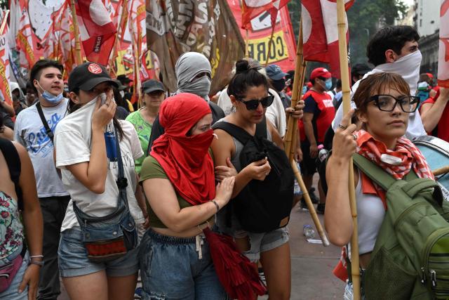 Demonstrators are affected by tear gas fired by riot police during a protest called by trade unionists against the labor reform debate taking place in the National Congress in Buenos Aires on February 11, 2026. Argentine police fired tear gas and used water cannon on February 11 to disperse demonstrators, who threw rocks and firebombs outside Congress during a Senate debate over radical labor reforms. (Photo by Luis ROBAYO / AFP)