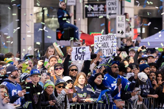 A fan holds an "ICE OUT" sign as he attends with many others the Seattle Seahawks' Superbowl LX victory parade in Seattle, Washington, on February 11, 2026. (Photo by Jason Redmond / AFP)