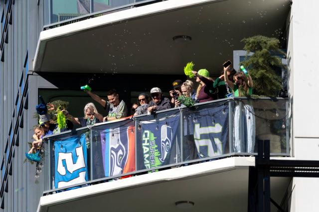 Seattle Seahawks' fans cheer from a balcony as they watch their team Superbowl LX victory parade in Seattle, Washington, on February 11, 2026. (Photo by Jason Redmond / AFP)