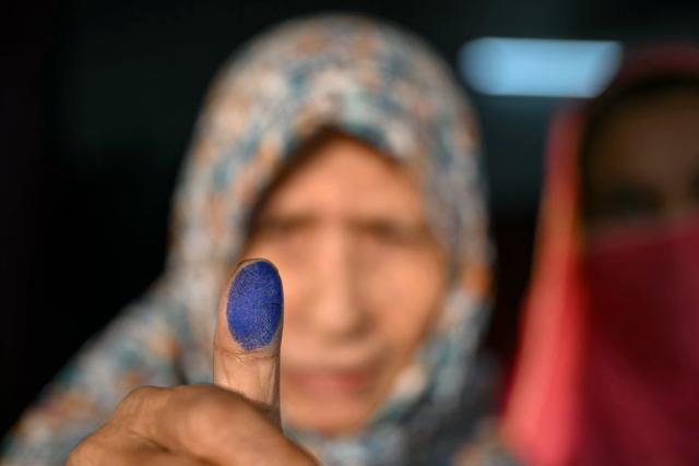 TOPSHOT - A voter holds up her inked finger after casting her vote at a polling station during Bangladesh's general election in Dhaka on February 12, 2026. (Photo by Sajjad HUSSAIN / AFP)