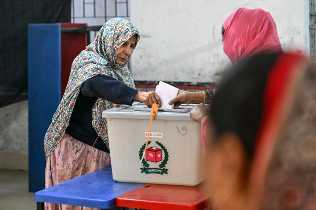 TOPSHOT - A voter (L) casts her vote at a polling station during Bangladesh's general election in Dhaka on February 12, 2026. (Photo by Sajjad HUSSAIN / AFP)