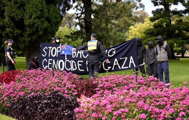 Police officers talk to protesters as they gather outside Government House upon the arrival of Israel’s President Isaac Herzog in Melbourne on February 12, 2026. Herzog's tightly secured, four-day trip aims to console Australia's Jewish community after the December shooting at Sydney's Bondi Beach that killed 15 people at a Hanukkah festival. (Photo by WILLIAM WEST / AFP)