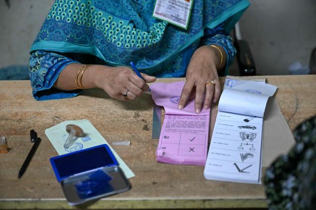 A polling officer prepares voting materials at a polling station during Bangladesh's general election in Dhaka on February 12, 2026. (Photo by MOHD RASFAN / AFP)