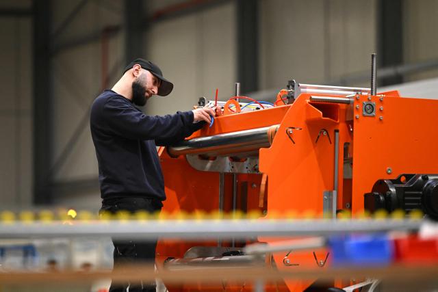 An employee works at a part of the tyre flipper for the tyre marking system at the headquarters of 4JET, a German firm that makes industrial laser processing technology, in Alsdorf, western Germany, on February 10, 2026. Insatiable demand in China for German exports, from cars to factory equipment, helped underpin a long boom in the eurozone's biggest economy. But times have changed: Chinese companies have become adept at making products long the specialities of manufacturers in Germany, adding to the headwinds that have left the country trapped in a seemingly endless decline. (Photo by Ina FASSBENDER / AFP)