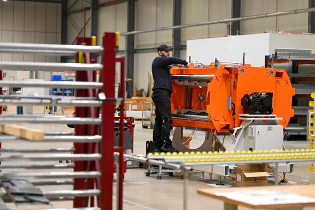 An employee works at a part of the tyre flipper for the tyre marking system at the headquarters of 4JET, a German firm that makes industrial laser processing technology, in Alsdorf, western Germany, on February 10, 2026. Insatiable demand in China for German exports, from cars to factory equipment, helped underpin a long boom in the eurozone's biggest economy. But times have changed: Chinese companies have become adept at making products long the specialities of manufacturers in Germany, adding to the headwinds that have left the country trapped in a seemingly endless decline. (Photo by Ina FASSBENDER / AFP)