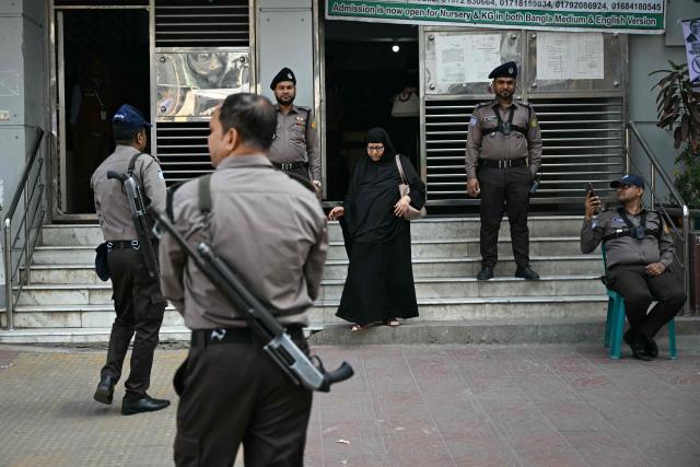 Security forces look on as a voter walks out from a polling station during Bangladesh's general election in Dhaka on February 12, 2026. (Photo by Sajjad HUSSAIN / AFP)
