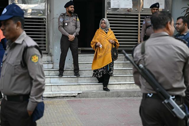 A woman (C) walks past police personnel after casting her ballot at a polling station during Bangladesh's general election in Dhaka on February 12, 2026. (Photo by Sajjad HUSSAIN / AFP)