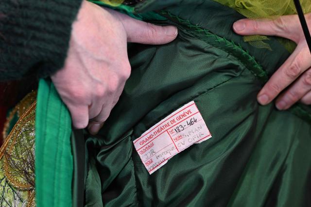 This photograph shows the label of a costume by Romanian costume designer Miruna Boruzescu for the Geneva opera house at a warehouse near Geneva on February 5, 2026, ahead of the Grand Theatre putting around 15,000 costumes, accessories and shoes up for sale. The Geneva opera house, the Grand Theatre, is parting with half of its stock: some 15,000 costumes, accessories and shoes, from major operatic and choreographic productions. The sales will take place on February 14th and 15th, with a time slot reserved for professionals. Prices range from 5 to 500 Swiss francs (from 5.45 euros to 545 euros). (Photo by Harold CUNNINGHAM / AFP)