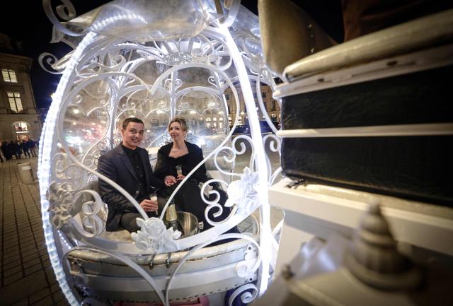 Dutch couple, Shirley Wijgaarts and Sander Castel, sit in a fairytale horse drawn carriage in Place Vendome during their marriage proposal, in central Paris, on February 07, 2026. In Paris, marriage proposals take on a cinematic flair, complete with Cinderella's carriage, private terraces, and bespoke scenarios, creating a lucrative market fueled by international clients. (Photo by STEPHANE DE SAKUTIN / AFP)