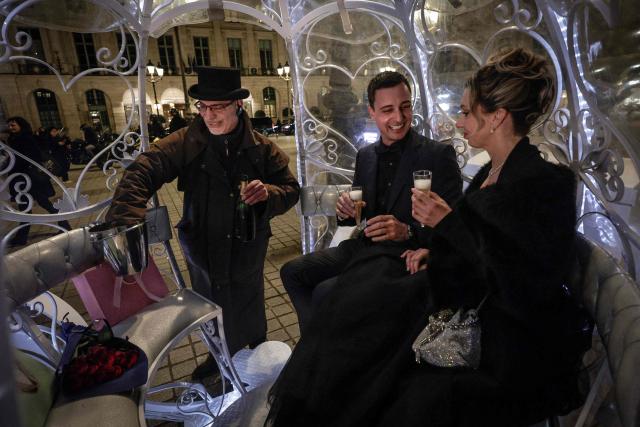Dutch couple, Shirley Wijgaarts and Sander Castel, drink Champagne in a fairytale horse drawn carriage in Place Vendome, in central Paris, on February 07, 2026. In Paris, marriage proposals take on a cinematic flair, complete with Cinderella's carriage, private terraces, and bespoke scenarios, creating a lucrative market fueled by international clients. (Photo by STEPHANE DE SAKUTIN / AFP)