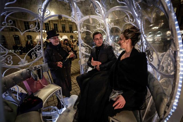 Dutch couple, Shirley Wijgaarts and Sander Castel, sit in a fairytale horse drawn carriage in Place Vendome, in central Paris, on February 07, 2026. In Paris, marriage proposals take on a cinematic flair, complete with Cinderella's carriage, private terraces, and bespoke scenarios, creating a lucrative market fueled by international clients. (Photo by STEPHANE DE SAKUTIN / AFP)