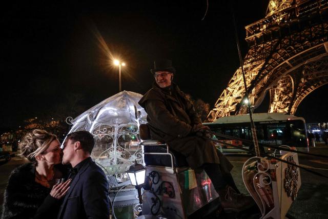 Dutch couple, Shirley Wijgaarts and Sander Castel, kiss in front of the Eiffel Tower as they participate in a marriage proposal, in central Paris, on February 07, 2026. In Paris, marriage proposals take on a cinematic flair, complete with Cinderella's carriage, private terraces, and bespoke scenarios, creating a lucrative market fueled by international clients. (Photo by STEPHANE DE SAKUTIN / AFP)