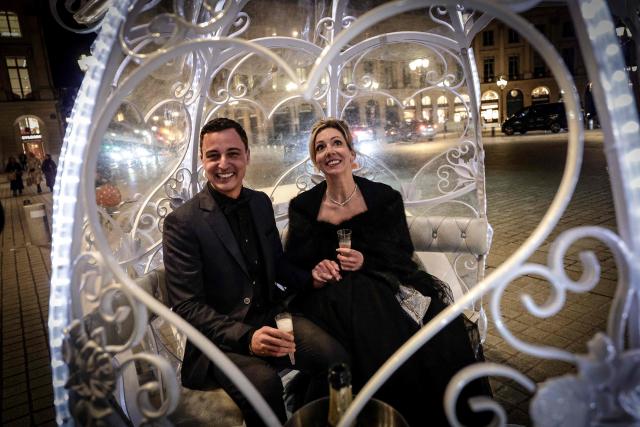 Dutch couple, Shirley Wijgaarts and Sander Castel, pose as they sit in a fairytale horse drawn carriage in Place Vendome during their marriage proposal, in central Paris, on February 07, 2026. In Paris, marriage proposals take on a cinematic flair, complete with Cinderella's carriage, private terraces, and bespoke scenarios, creating a lucrative market fueled by international clients. (Photo by STEPHANE DE SAKUTIN / AFP)
