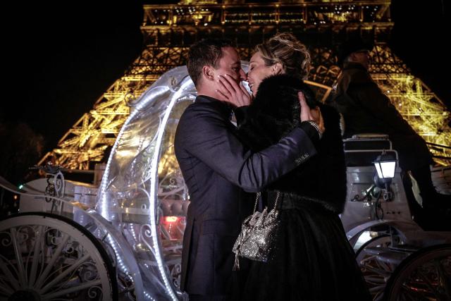 Dutch couple, Shirley Wijgaarts and Sander Castel, kiss in front of the Eiffel Tower as they participate in a marriage proposal, in central Paris, on February 07, 2026. In Paris, marriage proposals take on a cinematic flair, complete with Cinderella's carriage, private terraces, and bespoke scenarios, creating a lucrative market fueled by international clients. (Photo by STEPHANE DE SAKUTIN / AFP)