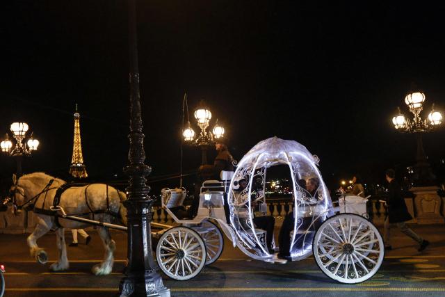 Dutch couple, Shirley Wijgaarts and Sander Castel, travel through central Paris in a fairytale horse drawn carriage during their marriage proposal, in Paris, on February 07, 2026. In Paris, marriage proposals take on a cinematic flair, complete with Cinderella's carriage, private terraces, and bespoke scenarios, creating a lucrative market fueled by international clients. (Photo by STEPHANE DE SAKUTIN / AFP)