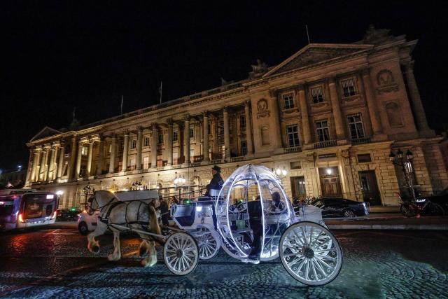 Dutch couple, Shirley Wijgaarts and Sander Castel, travel through central Paris in a fairytale horse drawn carriage during their marriage proposal, in Paris, on February 07, 2026. In Paris, marriage proposals take on a cinematic flair, complete with Cinderella's carriage, private terraces, and bespoke scenarios, creating a lucrative market fueled by international clients. (Photo by STEPHANE DE SAKUTIN / AFP)