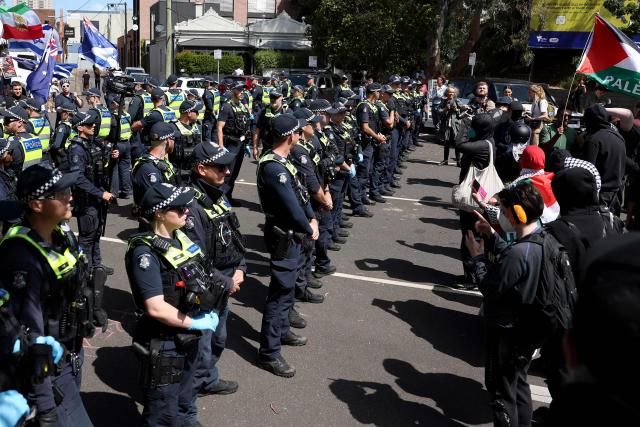 Protesters react towards police officers was they cordon off a venue during the visit of Israel’s President Isaac Herzog in Melbourne on February 12, 2026. Herzog's tightly secured, four-day trip aims to console Australia's Jewish community after the December shooting at Sydney's Bondi Beach that killed 15 people at a Hanukkah festival. (Photo by MARTIN KEEP / AFP)